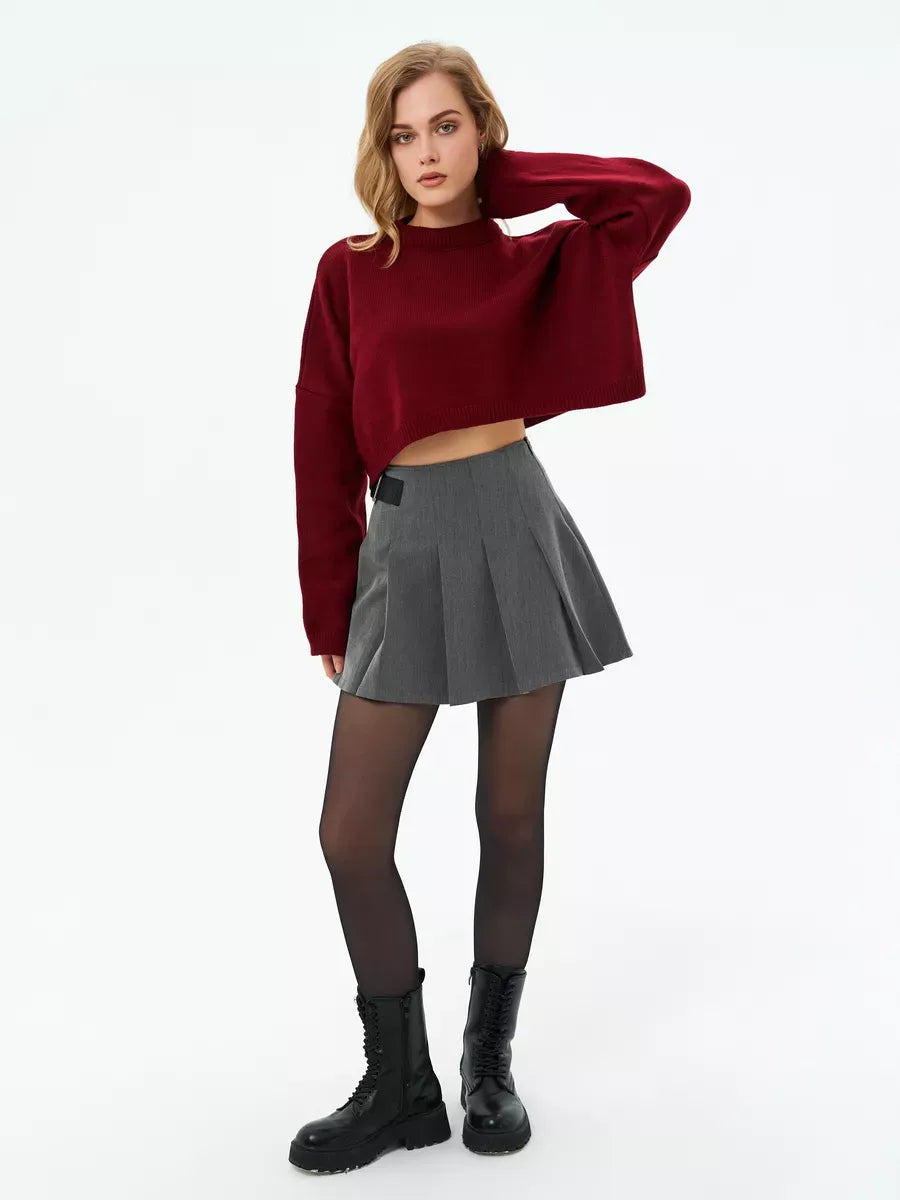 Model wearing the Garnet Sweater by Lauven, a cropped oversized knit in deep burgundy, paired with a pleated skirt.