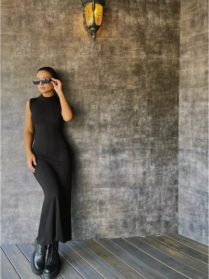 Leah Maxi Dress by Lauven - Black sleeveless bodycon gown with high neck collar and slim fit against a textured wall.