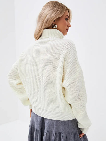 Rear view of a model wearing the Luaven Lyra Sweater, an oversized ivory knit with a high neck.