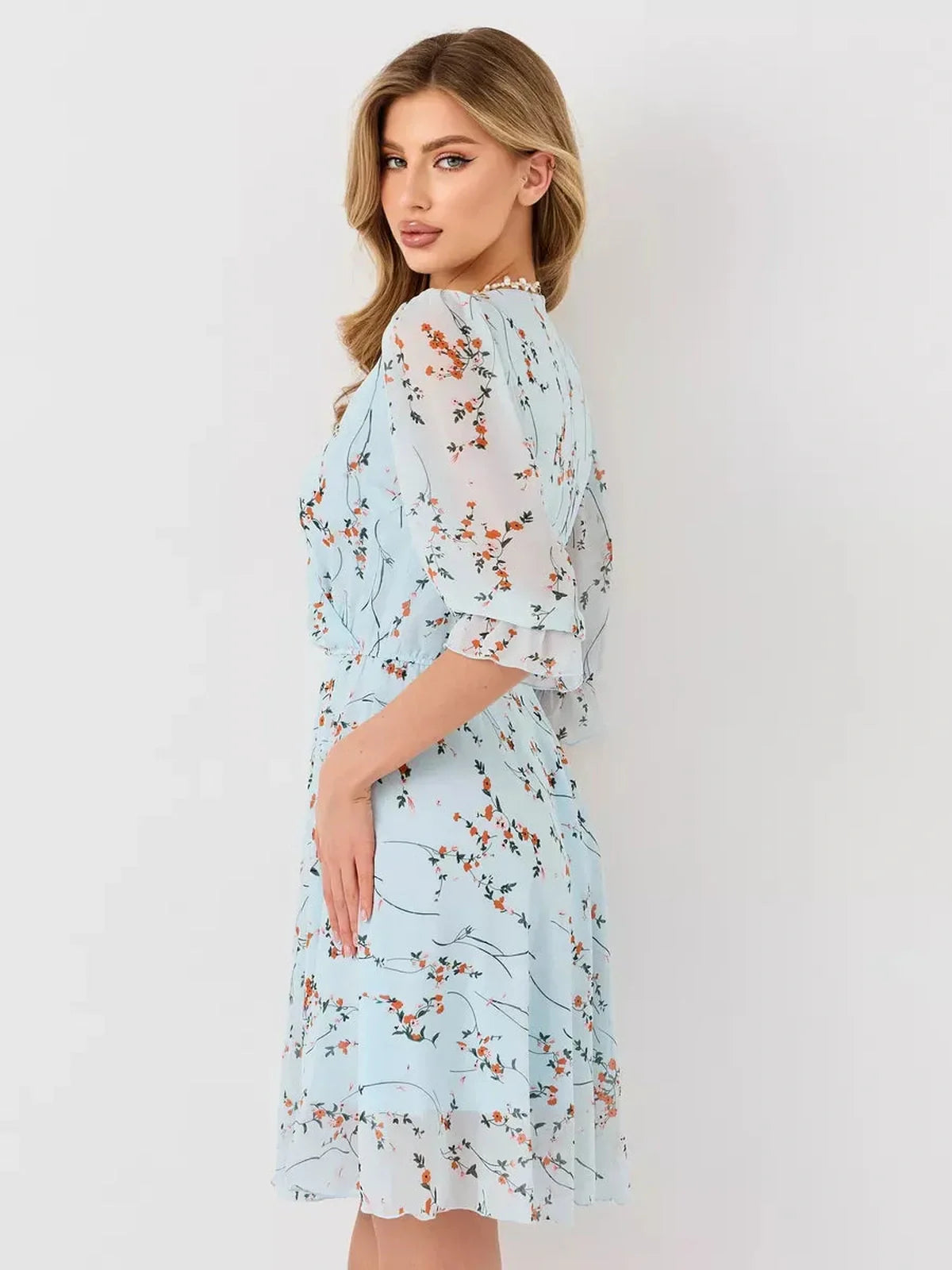 Mara Mini Dress by Lauven in light blue with floral design, featuring a wrap bodice and 3/4 sleeves.