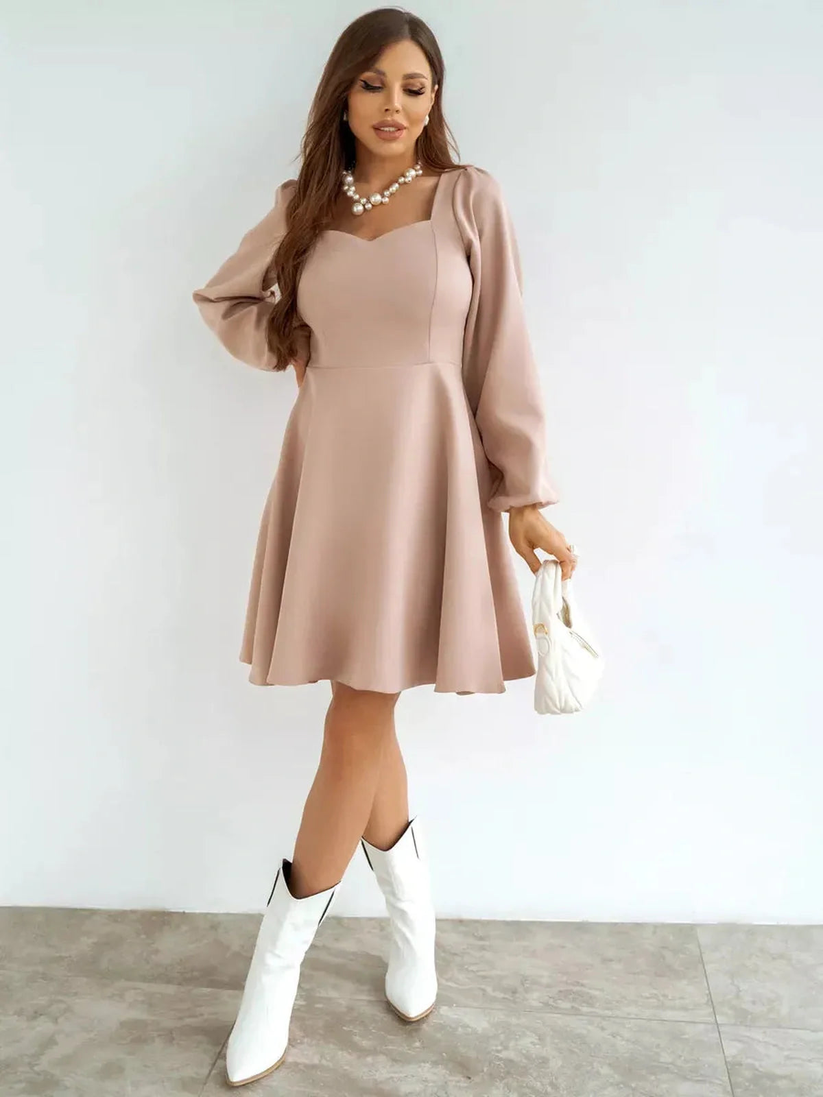 Milanese Mini Dress by Lauven in blush pink with A-line skirt and long sleeves, styled with white cowboy boots.