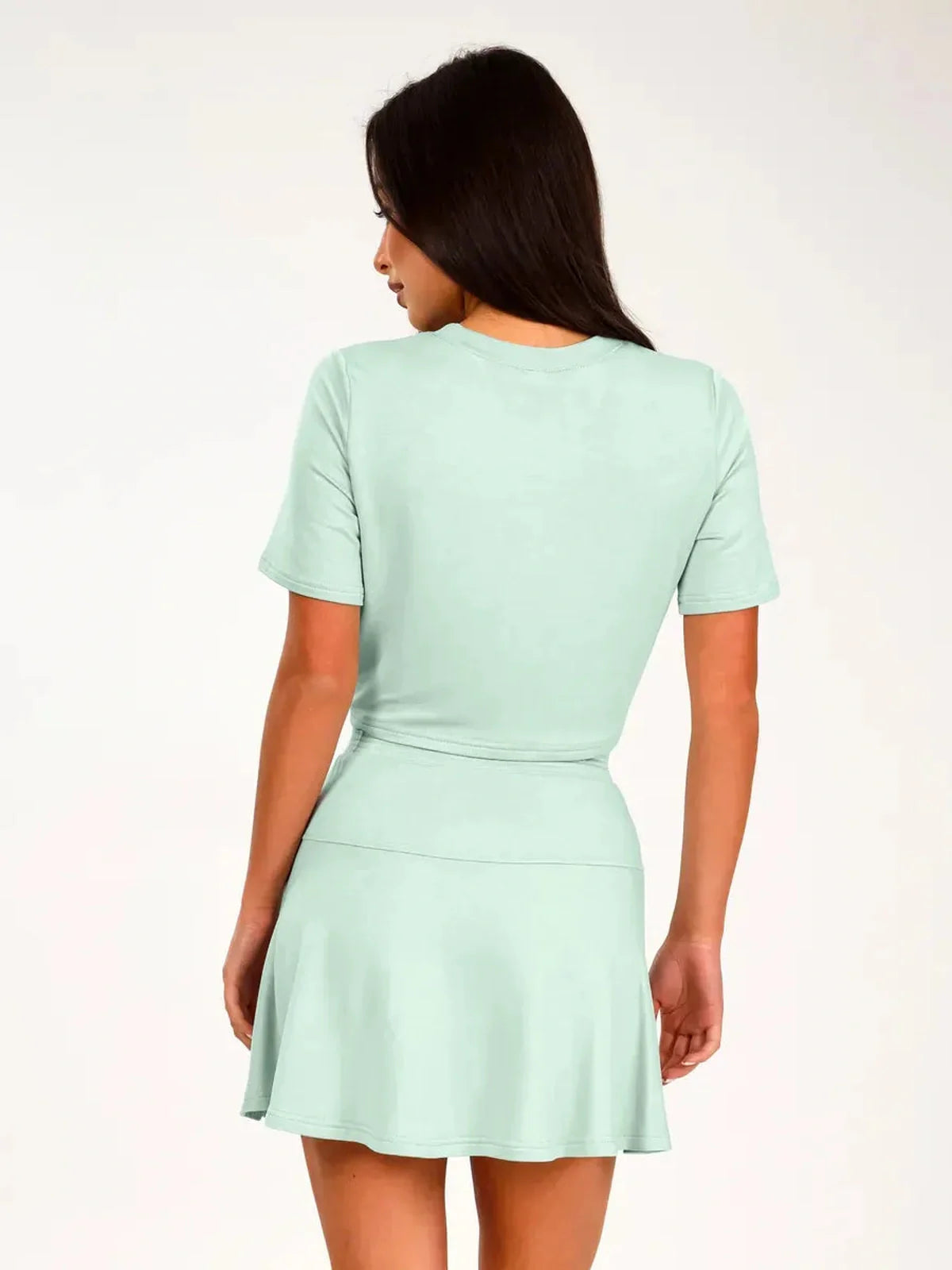 Mint Set – Back view of a woman wearing a mint green two-piece suit with a cropped top and flared mini skirt.