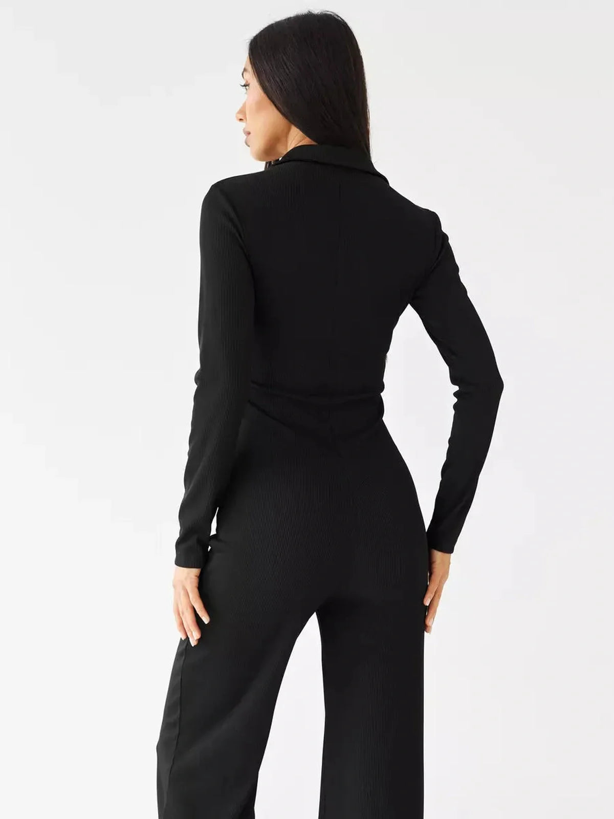 Model wearing the Nora Jumpsuit, showcasing the back view with ribbed knit fabric and tailored silhouette.