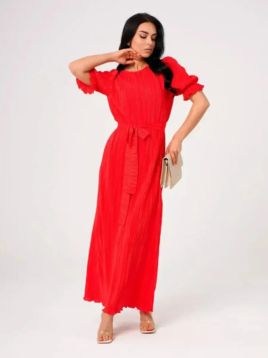 Model showcasing the Ophelia Maxi Dress in vibrant red, featuring pleated elegance and a belted waist for a feminine silhouette.