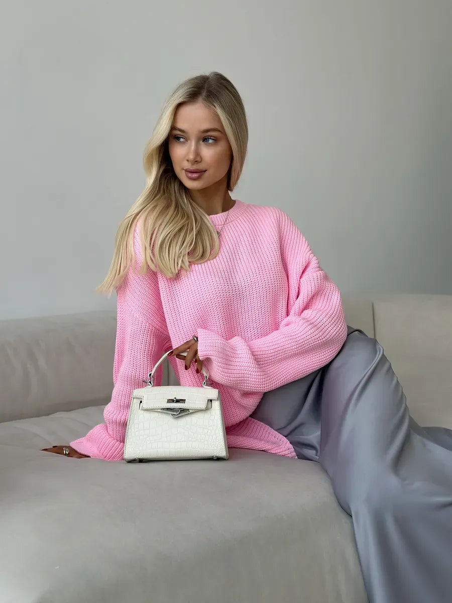 Model wearing a Poppy Sweater by Lauven, an oversized light pink knit with a relaxed fit, styled with a chic handbag.
