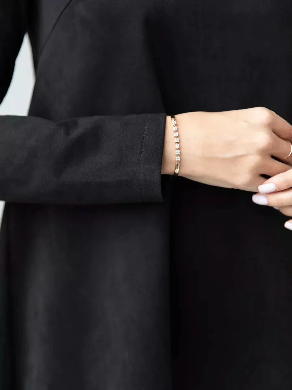Close-up of a hand wearing a bracelet, showcasing the sleeve of the Quinn Mini Dress by Lauven.