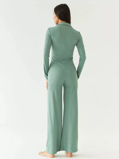 Model showcasing the back view of the Scarlett Jumpsuit in sage green with wide-leg silhouette and structured collar.