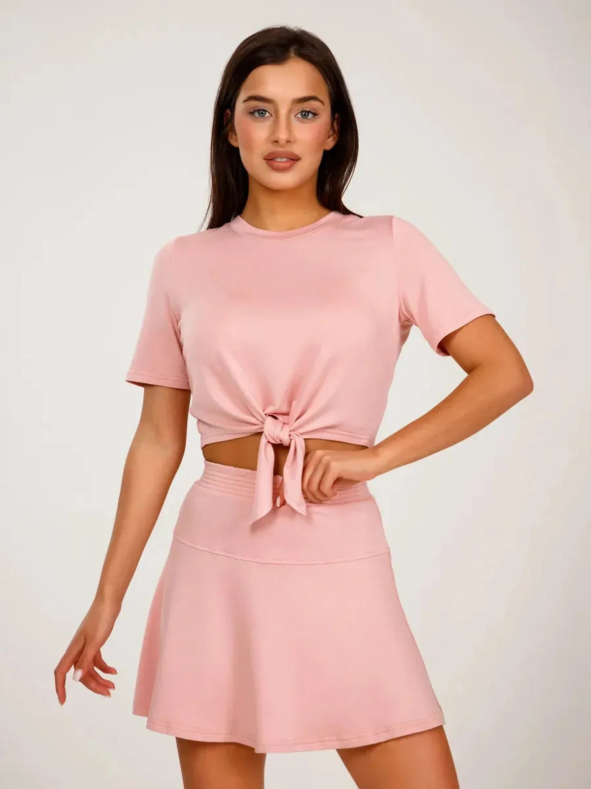 Serena Set women's two-piece cropped top and mini skirt in soft pink, featuring a tie front and flared design.