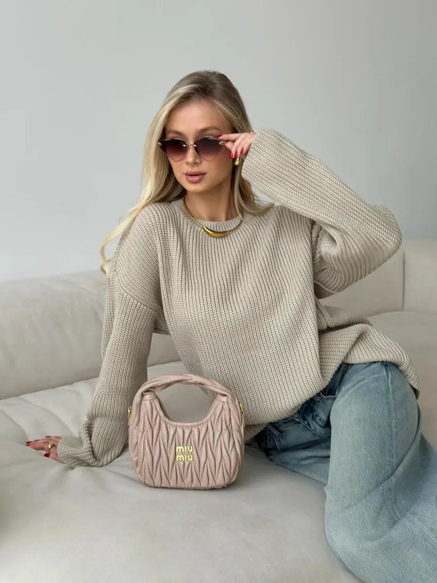 Model wearing a Sierra Sweater by Lauven, oversized beige knit with crew neck, paired with a stylish bag.