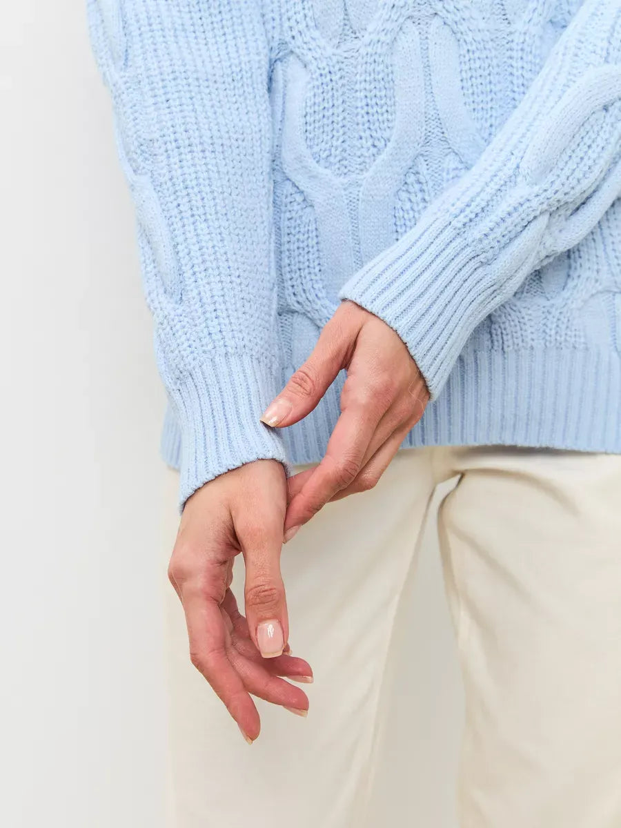 Skyline Knitwear women’s wool-blend turtleneck sweater by Lauven in soft pastel blue with cable-knit detail.