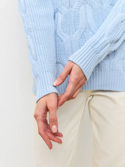 Skyline Knitwear women’s wool-blend turtleneck sweater by Lauven in soft pastel blue with cable-knit detail.