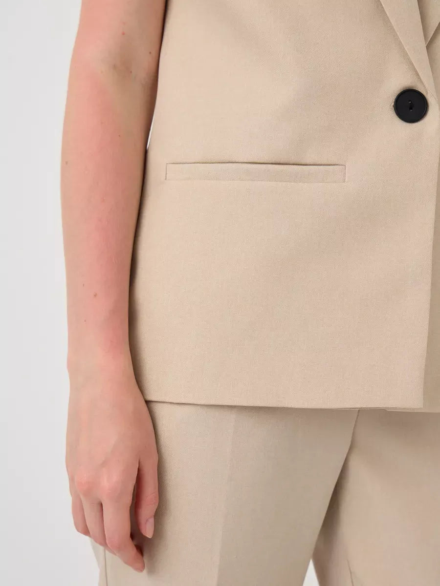 Close-up of Solara Suit Set by Lauven featuring a sleeveless beige vest and tailored high-waist pants.