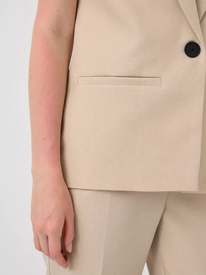 Close-up of Solara Suit Set by Lauven featuring a sleeveless beige vest and tailored high-waist pants.
