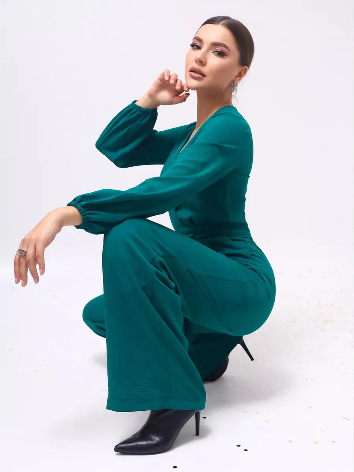 Zoe Jumpsuit in teal, featuring a deep V-neckline, wide-leg design, and long sleeves styled with subtle volume.