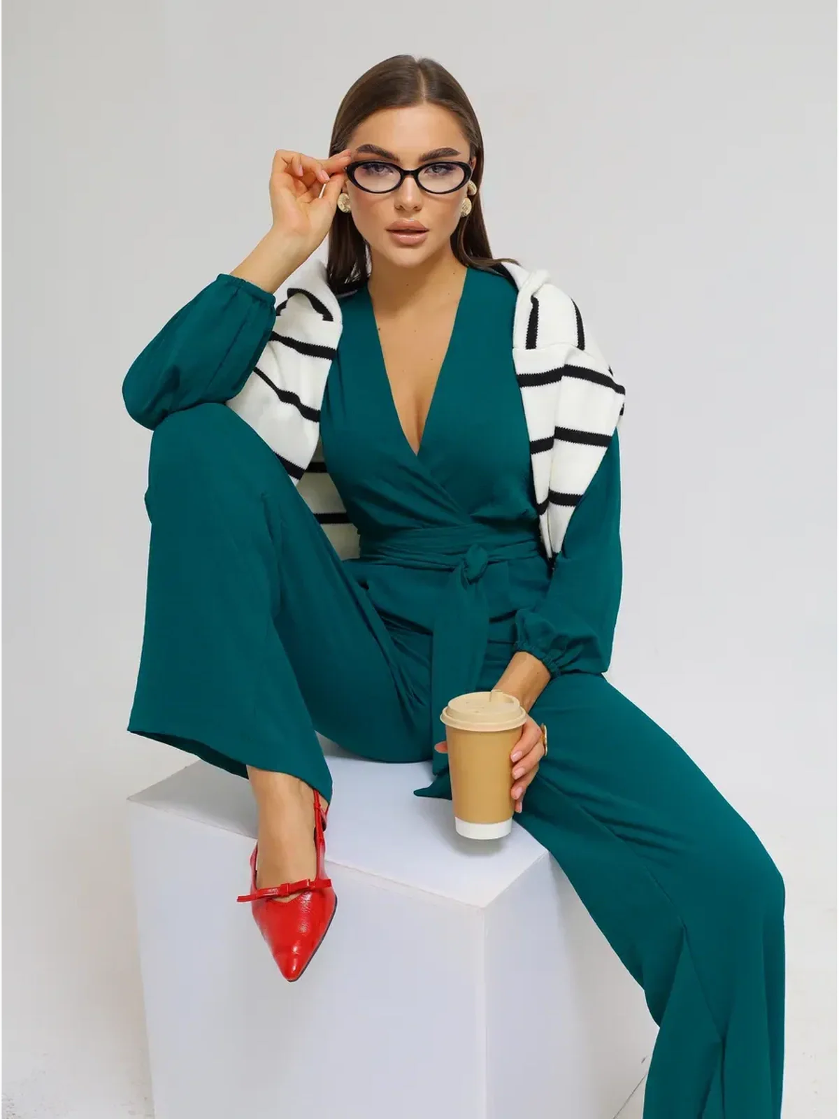 Zoe Jumpsuit modeled by a woman with glasses, featuring wide-leg trousers, a wrap-effect bodice, and a self-tie belt.