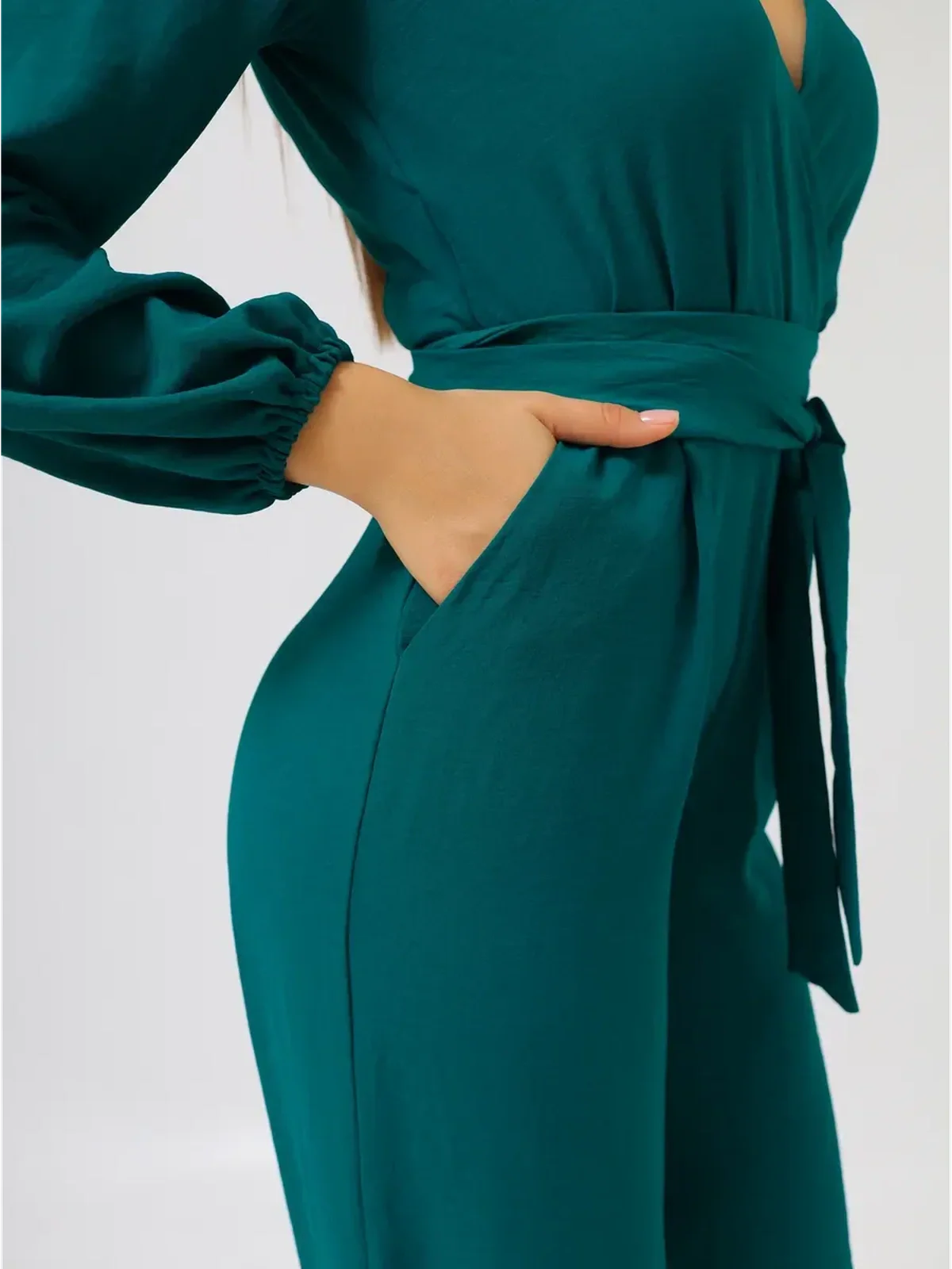 Detail of the Zoe Jumpsuit featuring a deep V-neckline, wide-leg silhouette, and self-tie belt with side pockets.