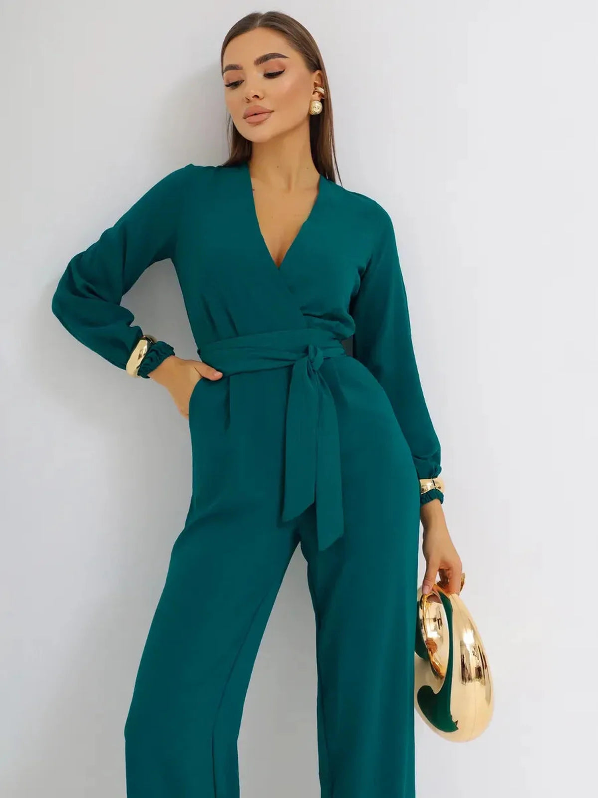 Zoe Jumpsuit in teal featuring a deep V-neckline, belted waist, wide-leg design, and elegant long sleeves.