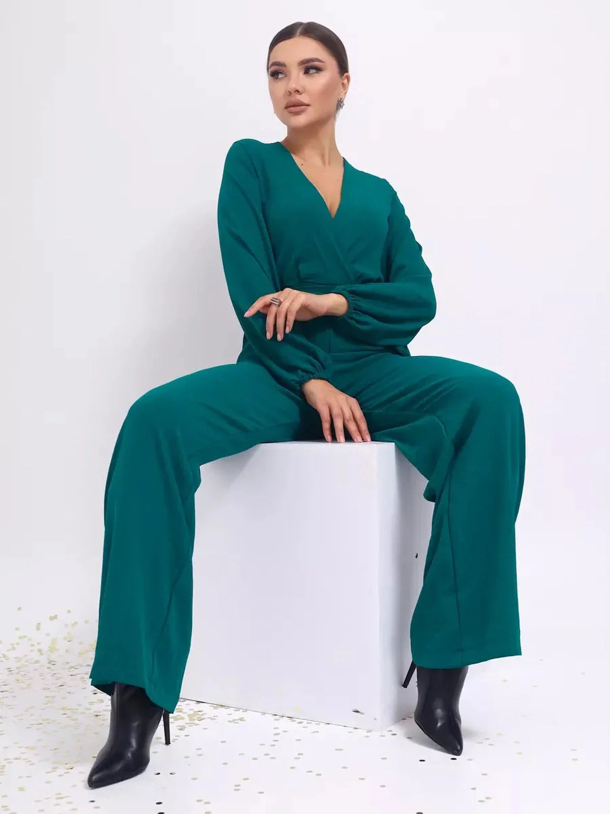 Zoe Jumpsuit – Wide-leg belted jumpsuit with deep V-neckline and long sleeves, worn by a model in teal.
