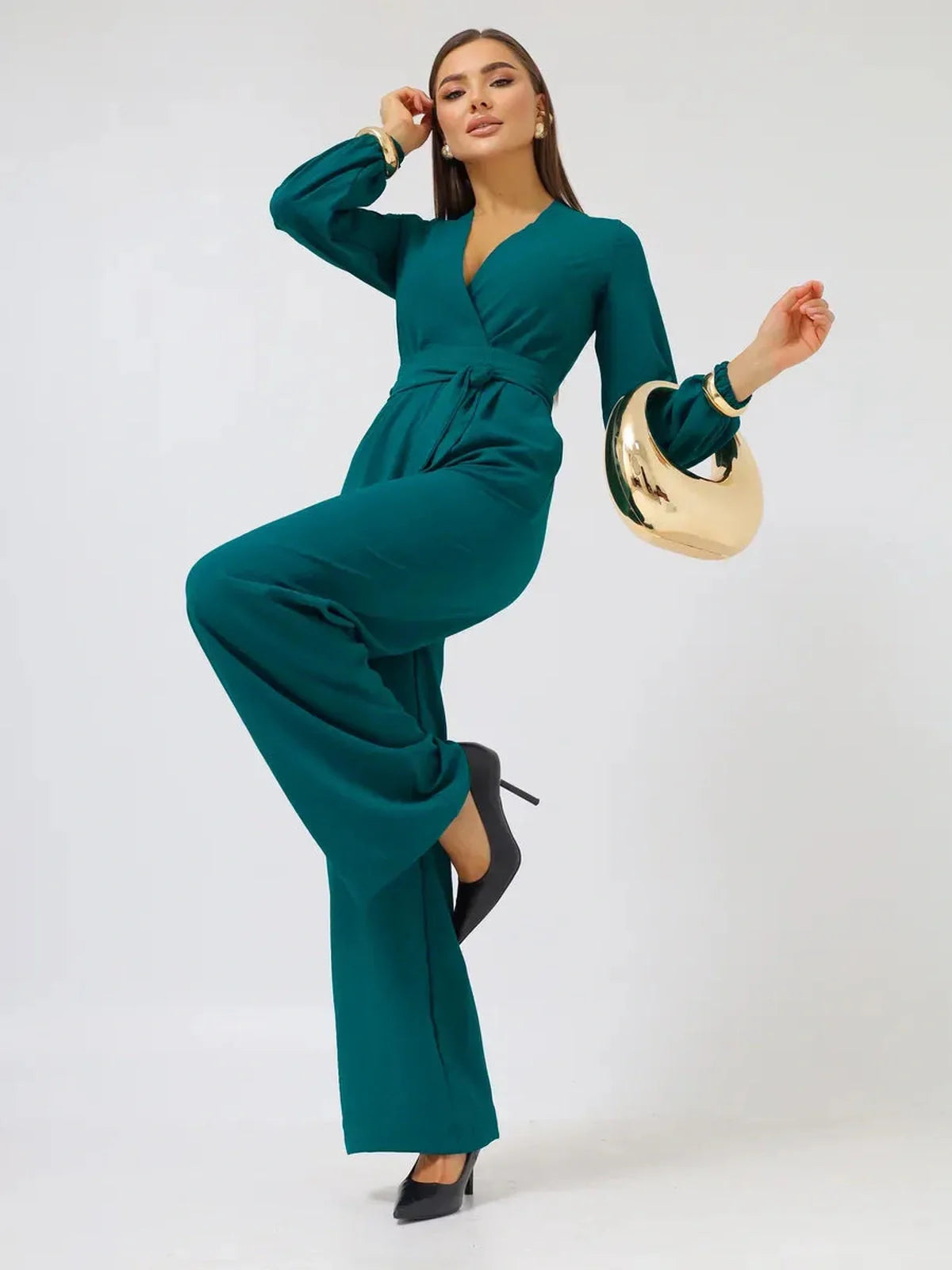 Zoe Jumpsuit in green featuring wide-leg trousers, a deep V-neckline, and long sleeves with volume at the cuffs.